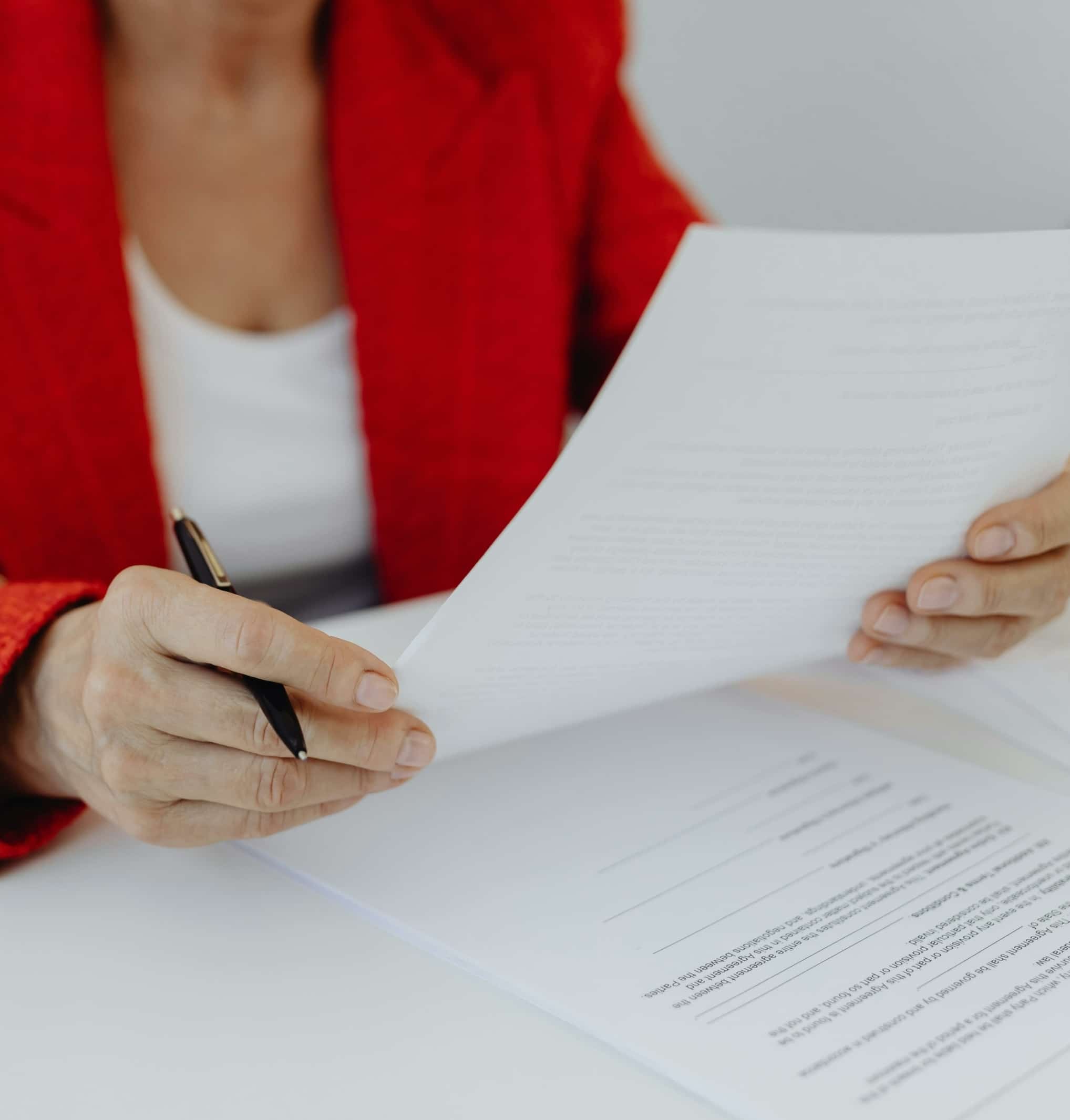 Une professionnelle relit un contrat, stylo à la main