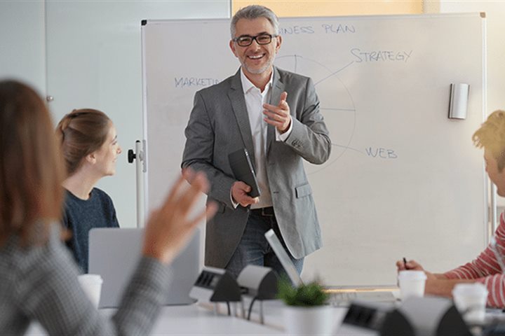 Formateur animant une session de formation devant un tableau blanc